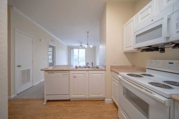 A kitchen with white appliances and wooden floors.
